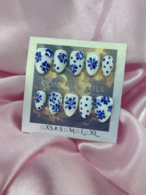 Bleu (S);Short Almond - Snygga handgjorda press-on naglar i vit bas med handmålade blå blommor och prickar. Naglarna har en kort mandelformad design och kommer i  S: 15 mm, 11,5 mm, 12 mm, 11 mm, 9 mm. Perfekt för dig som vill ha en unik och kreativ look på naglarna.