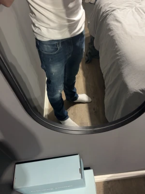 Blå slim fit jeans med slitningar  - Säljer ett par blå slim fit jeans med snygga slitningar och tvättade detaljer. Jeansen har klassisk femficksdesign och normal midja. Perfekta för en avslappnad och trendig look. Materialet är troligtvis bomull med lite stretch för extra komfort.