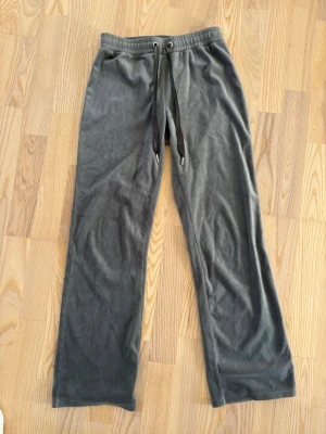 Grå mjukisbyxor från Gina Tricot - Mysiga grå mjukisbyxor från Gina Tricot med raka ben och dragsko i midjan. Tillverkade i ett mjukt och fleeceliknande material som känns skönt mot huden. Perfekta för chill dagar hemma eller när du vill vara bekväm.