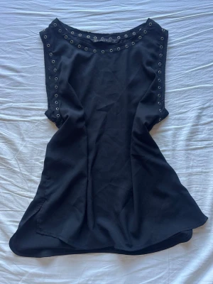 Svart ärmlös topp från Zara Basic - Snygg svart ärmlös topp från Zara Basic med silverfärgade nitar längs halsringning och sidor. 