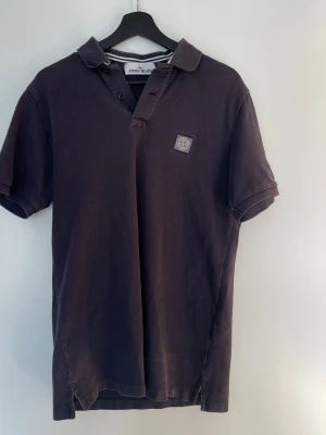 Stone Island pikétröja – Slim Fit – Strl L - Snygg och stilren pikétröja från Stone Island i mörkgrå färg. Klassisk design med ikoniska Stone Island-loggan på bröstet. Perfekt till både vardag och mer uppklädda outfits.  ✔ Storlek: L ✔ Passform: Slim fit ✔ Färg: Mörkgrå ✔ Skick: Bra skick ✔ Detaljer: Knäppning framtill + logga på bröst  ✅ Äkthet verifierad via QR-kod