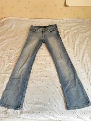 Vintage bootcut lågmidjade jeans - Snygga ljusblå lågmidjade bootcut jeans från HM med gul brodyr på bakfickorna. Jeansen har en lätt tvättad look och är tillverkade i denim med en skön passform. Står ingen lapp men skulle säga xs. Innerbenslängd 78cm och midjemått 36cm tvärs över. 