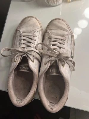 Vita sneakers Polo Ralph Lauren - Vita sneakers från Polo Ralph Lauren med guldfärgade detaljer och logga på sidan. Skorna har klassisk snörning och är tillverkade i syntetmaterial med en vit sula. Gör rent dom så gott jag kan innan jag skickar jag visar er bild innan!