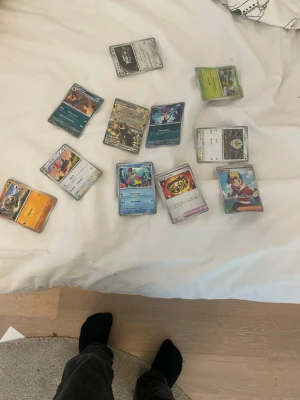 Blandade Pokémonkort samling - Säljer en samling blandade Pokémonkort med olika motiv, färger och typer. Korten har både klassiska och moderna illustrationer, vissa med holografiska detaljer. Perfekt för dig som vill utöka din samling eller börja spela Pokémon TCG.