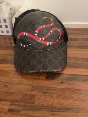 Gucci keps med orm och GG-mönster - Äkta Gucci keps till salu, kepsen har använts i 3 månader oregelbundet, fortfarande fräsch. Box och kvitto medföljer 