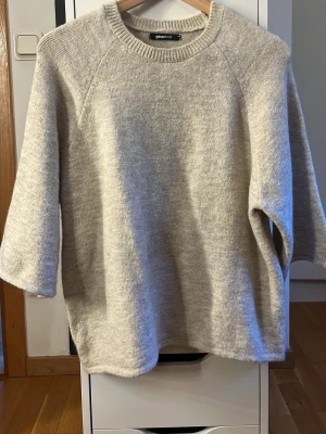 Beige stickad tröja från Gina Tricot - Mysig beige stickad tröja från Gina Tricot med rund halsringning och trekvartsärmar. Tröjan har en avslappnad passform och ribbade detaljer vid halsen. Pris kan diskuteras 