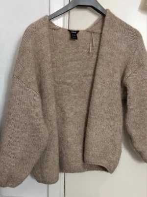 Beige stickad kofta från lindex - Mysig beige stickad kofta från lindex med öppen front och avslappnad passform. Koftan har långa ärmar och är gjord i ett mjukt, fluffigt material som passar perfekt för lager på lager. Enkel och stilren design som är lätt att matcha.