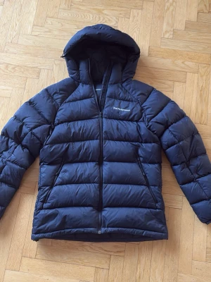 Svart peak performance dunjacka med huva - Snygg svart dunjacka från Peak Performance med huva och dragkedja framtill. Säljer eftersom den är för liten