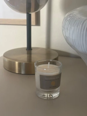 Doftljus Cashmere Rose Rituals - Säljer ett stilrent doftljus från Rituals i doften Cashmere Rose. Ljuset är vitt och kommer i ett genomskinligt glas med en elegant etikett. Perfekt för att skapa mysig stämning hemma.