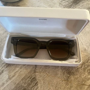 Gröna 04 chimi solglasögon - Snygga solglasögon med transparent grön båge och fyrkantig form. Glasen är bruna med en lätt toning. Ramen är i plast och har en modern, chunky design som sticker ut. Perfekta för dig som vill ha en cool och trendig accessoar till sommaren. Är i nyskick!! Endast testade💕