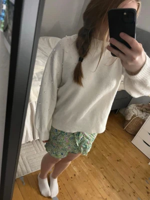 Gullig mönstrad grön kort kjol  - Snygg grön och mönstrad kjol. Kort och fin. Perfekt till i sommar. Den har knytning och volang, samt super fint mönster. Skönt tyg och bra passform. Stretchig och normal i storlek. 