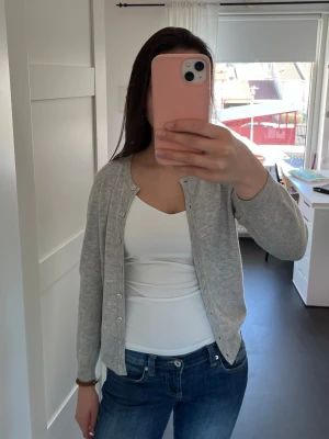 Ljusgrå kofta med knappar - En enkel och stilren ljusgrå kofta från Rosemunde. Koftan har långa ärmar och ribbade muddar vid ärmslut och nederkant. Pris går att diskutera💕