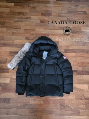Svart dunjacka från Canada Goose | Strl S - ❤️ Canada Goose Wyndham Parka Red Label – Svart (S) ❤️ Exklusiv och mycket varm vinterjacka från Canada Goose i Red Label-utförande med röd emblem och stilren premiumdesign. Mycket fint skick och redo för att skickas ut! Perfekt för nordiskt klimat med tjock dunfyllning, skyddande huva och djupa dragkedjefickor. En lyxig och praktisk vinterfavorit.  📦 Snabb leverans – skickas samma dag 📩 (såvida inga hindr.) Skriv vid intresse