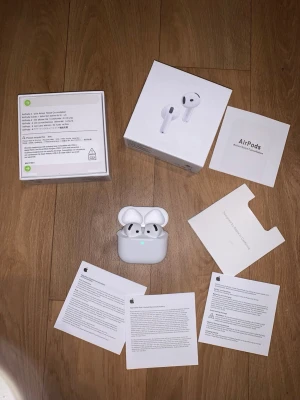Apple AirPods 4 - Säljer ett par vita Apple AirPods Pro med trådlöst laddningsetui. Hörlurarna har en stilren och kompakt design i blank plast och levereras med originalförpackning och manualer. Perfekta för dig som vill ha grymt ljud och smidig anslutning till din iPhone.