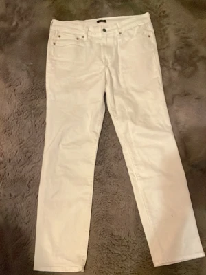 Vita raka jeans - Säljer ett par vita jeans med rak passform och klassisk femficksdesign. Jeansen har knappgylf och bälteshällor. Perfekta för dig som vill ha en clean och stilren look. Materialet känns som bomull med lite stretch.