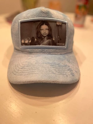 Ljusblå truckerkeps med fotoapplikation - Ljusblå keps med Adriana Lima på. Den är från onecap 