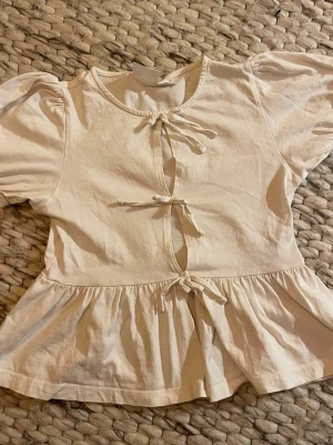 Vit blus med knyt från Gina Tricot - Supersöt vit blus från Gina Tricot med puffärmar och tre knyt framtill.