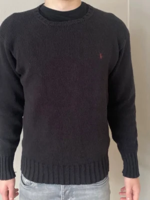 Svart stickad tröja från Ralph Lauren - Svart stickad tröja från Ralph Lauren med röd/brun logga broderad på bröstet. Perfekt för dig som gillar klassisk och enkel stil. Gammal modell som inte säljs längre så passa på att få en snygg tröja för bra pris! postar inom 24h📦 köp budle på mer än ett plagg för 10% rabatt!🤝
