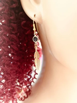 By prisförslag- 1 st Guldörhängen med fjäder och svart sten - Snyggt örhängen i guldfärg med en liten svart sten och en hängande fjäderdetalj. Örhängena har krokfäste och en stilren, bohemisk känsla. Perfekta för dig som vill ha något unikt och trendigt i smyckeskrinet.