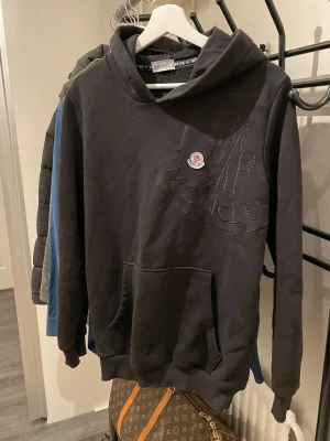 Moncler hoodie - Svart hoodie från Moncler med stor broderad logga och patch på bröstet. Aa vill helt ärligt bara få bort den för den används inte och har bara legat i garderoben i ett par år nu. 🔥Bara höra av sig i dm vid frågor och funderingar!🔥