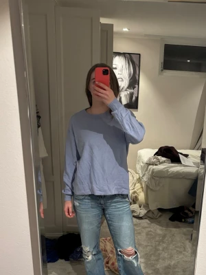 Ljusblå långärmad tröja med knappar - Ljusblå långärmad tröja i mjukt material med rund halsringning. Snygg detalj med tre knappar längs ena sidan nedtill. Perfekt för en avslappnad och stilren look.