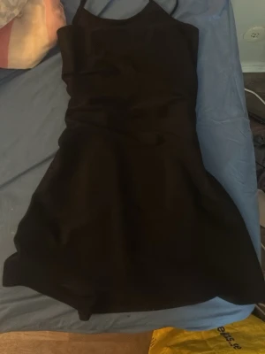 Svart kort klänning med smala axelband - Säljer en svart kort klänning med smala axelband och figurnära passform upptill. Klänningen har en lätt utsvängd kjol och enkel, stilren design. Perfekt för dig som gillar minimalistisk stil.