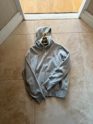  Ralph Lauren hoodie! - Snygg grå hoodie från Polo Ralph Lauren! Knappt använd då hoodien nästan aldrig kommer till användning. Skicket är som ny. Pris går att diskutera vid snabbt köp!