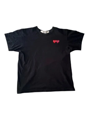 Svart t-shirt från Comme des Garçons - Säljer en svart t-shirt från Comme des Garçons med två röda hjärtan med ögon broderade på bröstet. T-shirten har en normal passform och är kortärmad. Perfekt för en stilren look! Det står storlek M men skulle säga att den sitter mer som S