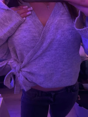  wraped cardigan Lager 157 - Mysig grå Lager 157 omlottkofta med knytband i sidan och långa ärmar. Koftan har en djup v-ringning och är tillverkad i ett mjukt stickat material. Perfekt att slänga på sig över ett linne eller t-shirt för en avslappnad look.