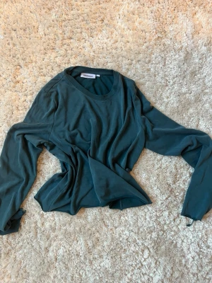 Mörkgrön långärmad t-shirt Weekday - Snygg mörkgrön långärmad t-shirt från Weekday i mjuk bomull. Enkel och clean design med rund halsringning och relaxed fit. Perfekt basplagg att styla med allt.