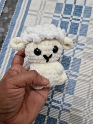 Virkad vit lammfigur - Söt handgjord virkad lammfigur i mjukt vitt garn med stora svarta ögon och små öron. Perfekt som dekoration eller present till någon som gillar gulliga saker. Figurerad kropp och fluffig struktur ger ett mysigt intryck.