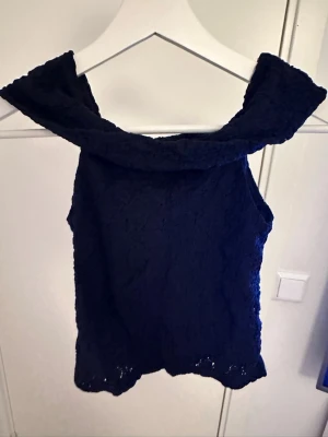 Mörkblå spets topp med bred krage - Snygg mörkblå ärmlös topp med bred krage och spetsdetaljer. Passar XS