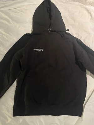 Svart hoodie från Halowear med tryck - Svart hoodie från Halowear med liten vit logga på bröstet och stort tryck på ryggen med texten 'eunoia' och dess betydelse. 