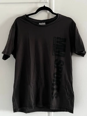 Gröngrå MM Sports t-shirt Army Edition XXL - Gröngrå t-shirt från MM Sports, army Edition med tryck både fram och bak. Klassisk passform och rund halsringning. En enkel snygg t-shirt med statement-tryck. Ganska liten 2xl. 