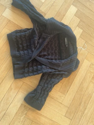 Svart quiltad kofta från Bik Bok - Snygg svart kofta från Kappahl med mönster och bred krage. Koftan har trekvarts ärmar