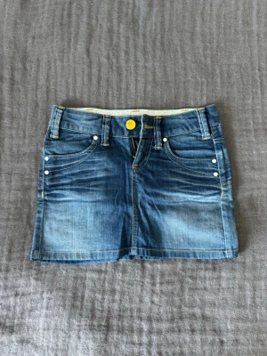 Lågmidjad jeanskjol - Snygg blå lågmidjad jeanskjol med jätte skön passform. Kjolen har en kort modell och har perfekt längd. Tyvärr är den för liten för mig nu så därför säljer jag. Kjolen är i jätte bra skick och super snygg till våren och sommar! Fråga om mått!