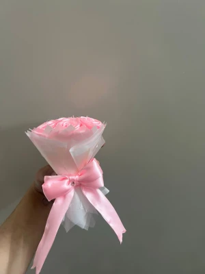 Mini bukett med rosa konstrosor - Söt liten bukett med ljusrosa konstgjorda rosor, inslagna i vitt papper och dekorerad med en rosa sidenrosett. Perfekt som present eller dekoration. Rosorna är gjorda av plast och tyg för ett realistiskt utseende.
