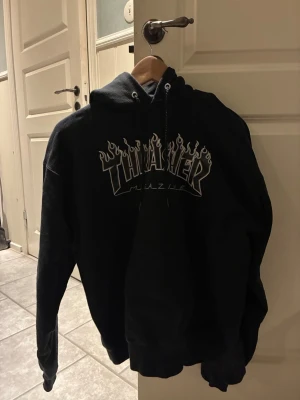 Svart Thrasher hoodie med flames - Säljer en svart hoodie från Thrasher med flames-loggan i vitt, inget fel på den har bara inte användning av den💞