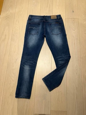 Mörkblå jeans från Nudie Jeans - Snygga mörkblå jeans från Nudie Jeans med klassisk femficksmodell och slitningar på knäna. Jeansen har en smal passform och är tillverkade i denim med coola tvättade detaljer. Perfekta för en avslappnad och trendig look. W30 L27