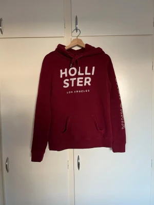 Röd Hollister hoodie - En snygg röd hoodie från Hollister med tryck fram och på vänster arm. Storlek S men skulle säga att den är lite stor i storleken.