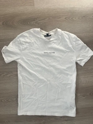 Vit t-shirt från Icono Couture - Säljer en vit t-shirt från Icono Couture med relaxed fit och diskret logga på bröstet. T-shirten har korta ärmar och är gjord i mjuk bomull, perfekt för en clean och enkel stil. Helt ny oanvänd 