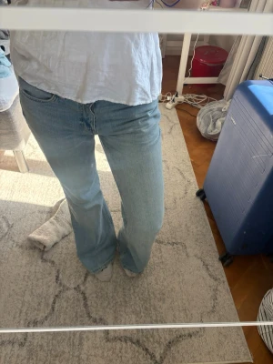 Ljusblå bootcut jeans - Säljer ett par ljusblå bootcut jeans med klassisk femficksdesign och medelhög midja. Jeansen har en avslappnad passform över låren och utsvängda ben. Perfekta för en trendig och avslappnad stil. Materialet är denim i bomull. De är långa och sitter perfekt i längden på mig som är 175