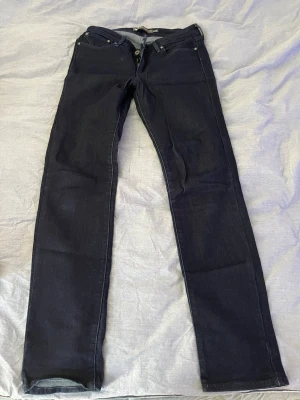 Levi's Slim Mid Rise Jeans blå - Mörkblå jeans från Levi's Slight Curve-kollektion med slim fit och mid rise. Klassisk femficksmodell med dragkedja och knapp. Snygg, enkel design som passar till det mesta. Perfekta för dig som gillar en smalare siluett och tidlös look.