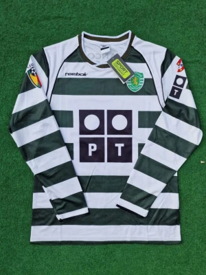 Sporting Lissabon långärmad matchtröja - Långärmad matchtröja från Sporting Lissabon med gröna och vita horisontella ränder. Tröjan har klubbmärke på bröstet, sponsorloggor och nummer 28 med namnet C. Ronaldo på ryggen. Materialet är lätt och andas, perfekt för fotboll och träning.