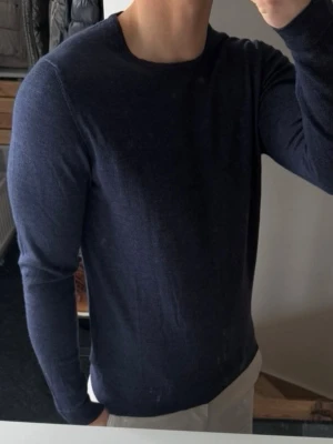 Mörkblå tröja från J.Lindeberg - Snygg mörkblå långärmad tröja från J.Lindeberg. Tröjan har rund halsringning och en stilren, minimalistisk design som passar perfekt till jeans eller chinos. 100% merinoull. Storlek m men är liten i storlek. Så sitter som xs