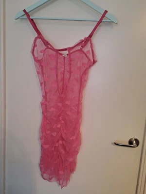 Rosa transparent nattlinne med hjärtan - Säljer ett rosa nattlinne i transparent mesh med tunna axelband och volangdetaljer. Tyget har ett mönster av små hjärtan och nattlinnet har en figurnära passform. Str s. Kan även vara väldigt snygg i layering 🩷