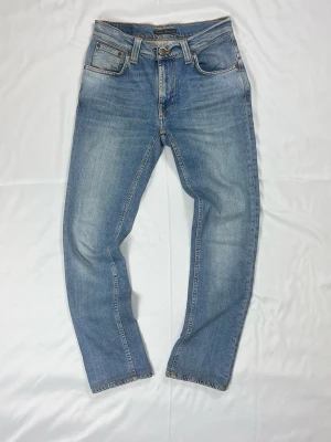 Nudie Jeans Thin Finn – Ljusblå Wash – W28/L32 Stilrena jeans från Nudie  - Färg: Ljusblå denim | Modell: Thin Finn, slim fit | Storlek: W28/L32 | Skick: Grade C+, 7/10 (slitage & blekning) | Stretchig & bekväm | Hör av dig vid frågor!