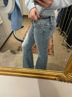 Ljusblå bootcut jeans med medel hög midja  - Säljer ett par ljusblå jeans med bootcut-modell och medel hög midja. Jeansen har klassiska fem fickor. Materialet är denim i bomull och passformen är slim upptill med utsvängda ben. Säljer eftersom dom är lite för stora i benen. Skriv om ni har några frågor!