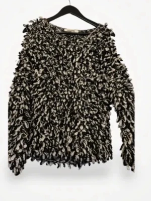 Isabel marant tröja - Unik stickad tröja i svart och vitt med fluffig, loopy textur. Tröjan har rund halsringning och långa ärmar. Materialet är tjockt garn som ger en cool och trendig look. Perfekt för dig som vill sticka ut med din outfit. Har ett hål vid axeln se bild ovan