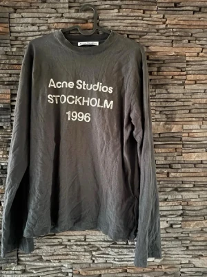 Svart långärmad Acne Studios t-shirt - Cool svart långärmad t-shirt från Acne Studios med trycket 'Acne Studios STOCKHOLM 1996' på bröstet. Klassisk rund hals och relaxed fit. Perfekt för dig som gillar minimalistisk och stilren design.